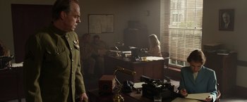 Movie still from “Hacksaw Ridge” (2016), directed by Mel Gibson – A man in a military uniform standing in front of a desk; Medium shot, Low angle