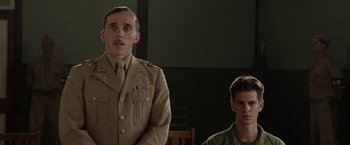 Movie still from “Hacksaw Ridge” (2016), directed by Mel Gibson – A man in a military uniform standing next to another man; Medium shot, Low angle