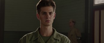 Movie still from “Hacksaw Ridge” (2016), directed by Mel Gibson – A young man in a green shirt is looking at the camera; Close Up shot, Low angle