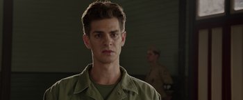 Movie still from “Hacksaw Ridge” (2016), directed by Mel Gibson – A man in a green shirt is looking straight ahead; Close Up shot, Low angle