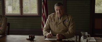 Movie still from “Hacksaw Ridge” (2016), directed by Mel Gibson – An older man in a uniform sitting at a table writing; Medium shot, Low angle