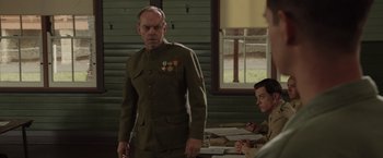 Movie still from “Hacksaw Ridge” (2016), directed by Mel Gibson – A man in a military uniform standing in front of two other men; Medium shot, Over the shoulder angle