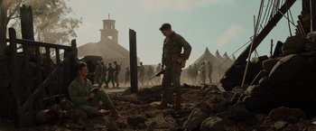 Movie still from “Hacksaw Ridge” (2016), directed by Mel Gibson – A man holding a gun while standing next to a pile of dirt; Wide shot, Low angle