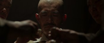 Movie still from “Hacksaw Ridge” (2016), directed by Mel Gibson – A man with a bald head is looking down at his fingers; Close Up shot, Low angle