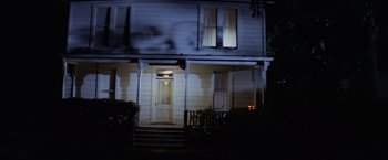 Movie still from “Halloween” (1978), directed by John Carpenter – A white house with a porch lit up at night; Wide shot, Low angle