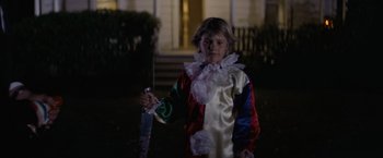Movie still from “Halloween” (1978), directed by John Carpenter – A child dressed up as a clown holding an umbrella in front of a house; Medium shot, High angle