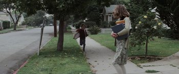 Movie still from “Halloween” (1978), directed by John Carpenter – A young girl running down a sidewalk while a younger girl holds a book; Wide shot, Over the shoulder angle
