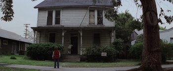 Movie still from “Halloween” (1978), directed by John Carpenter – A woman standing on the sidewalk in front of an old house; Wide shot, Low angle