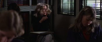 Movie still from “Halloween” (1978), directed by John Carpenter – A woman sitting in front of a window holding a pencil; Medium shot, Over the shoulder angle