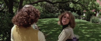 Movie still from “Halloween” (1978), directed by John Carpenter – Two women are talking in a park with trees in the background; Medium shot, Over the shoulder angle