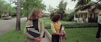 Movie still from “Halloween” (1978), directed by John Carpenter – Two women are standing on a sidewalk holding books; Medium shot, Low angle