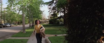 Movie still from “Halloween” (1978), directed by John Carpenter – A woman walking down a sidewalk in a park; Wide shot, High angle
