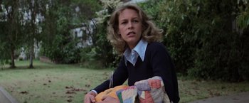 Movie still from “Halloween” (1978), directed by John Carpenter – A woman holding a quilt in a yard; Close Up shot, High angle