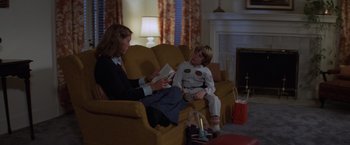 Movie still from “Halloween” (1978), directed by John Carpenter – A woman sitting on a couch next to a boy; Medium shot, Over the shoulder angle