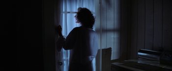 Movie still from “Halloween” (1978), directed by John Carpenter – A woman standing in front of a window at night; Medium shot, Low angle
