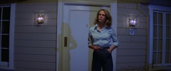 Movie still from “Halloween” (1978), directed by John Carpenter – A woman standing in front of a white door; Medium shot, Low angle