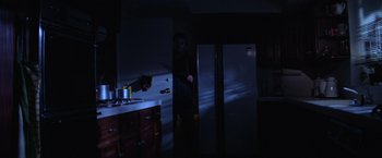 Movie still from “Halloween” (1978), directed by John Carpenter – A person standing in a kitchen in front of an open refrigerator; Medium shot, Low angle