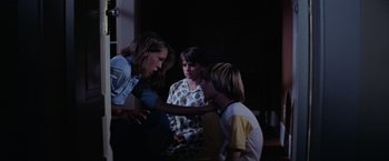 Movie still from “Halloween” (1978), directed by John Carpenter – A group of people standing around each other in the dark; Medium shot, Over the shoulder angle