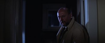Movie still from “Halloween” (1978), directed by John Carpenter – A man in a suit and tie standing in a dark room; Close Up shot, Low angle