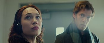 Movie still from “Halloween” (2018), directed by David Gordon Green – A woman with headphones on looking up at a man; Close Up shot, Low angle