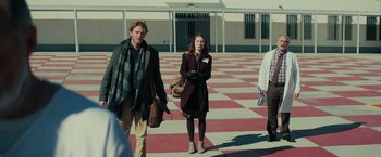 Movie still from “Halloween” (2018), directed by David Gordon Green – A group of people walking across a checkerboard floor; Wide shot, Over the shoulder angle