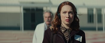 Movie still from “Halloween” (2018), directed by David Gordon Green – A woman wearing headphones while standing in front of a man; Close Up shot, Over the shoulder angle