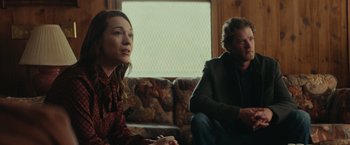 Movie still from “Halloween” (2018), directed by David Gordon Green – A woman and a man sitting on a couch in front of a window; Medium shot, Over the shoulder angle