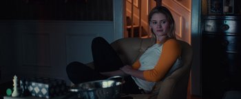 Movie still from “Halloween” (2018), directed by David Gordon Green – A woman sitting on a couch in front of a bowl; Medium shot, Over the shoulder angle