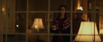 Movie still from “Halloween” (2018), directed by David Gordon Green – A woman standing in a living room holding a cup; Medium shot, Over the shoulder angle