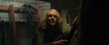 Movie still from “Halloween” (2018), directed by David Gordon Green – An older woman sitting in front of a brick wall; Medium shot, Over the shoulder angle