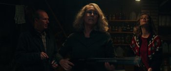 Movie still from “Halloween” (2018), directed by David Gordon Green – A woman holding an electric guitar in a dark room; Medium shot, Low angle