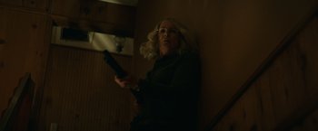 Movie still from “Halloween” (2018), directed by David Gordon Green – A woman holding a remote control in her hand; Medium shot, Low angle