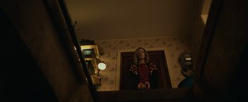 Movie still from “Halloween” (2018), directed by David Gordon Green – A woman standing in front of a mirror in a living room; Medium shot, Low angle