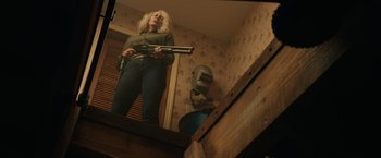 Movie still from “Halloween” (2018), directed by David Gordon Green – A woman holding a gun while standing in a room; Medium shot, Low angle
