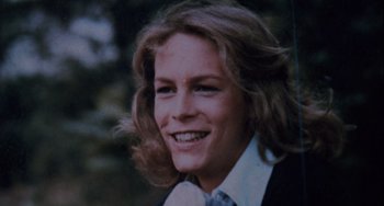 Movie still from “Halloween 4: The Return of Michael Myers” (1988), directed by Dwight H. Little – A person wearing a suit and tie smiling; Extreme Close Up shot, Overhead angle