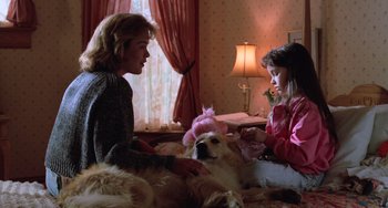 Movie still from “Halloween 4: The Return of Michael Myers” (1988), directed by Dwight H. Little – A woman and a girl sitting on a bed with a dog; Medium shot, Over the shoulder angle