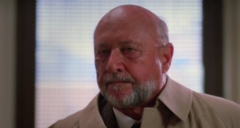 Movie still from “Halloween 4: The Return of Michael Myers” (1988), directed by Dwight H. Little – An older man with a bald head wearing a shirt and tie; Close Up shot, Low angle