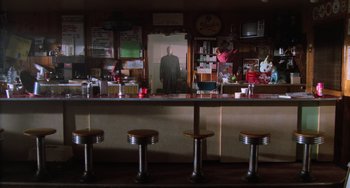 Movie still from “Halloween 4: The Return of Michael Myers” (1988), directed by Dwight H. Little – A man is standing in the reflection of a mirror in a bar; Wide shot, Low angle