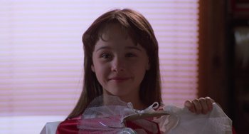 Movie still from “Halloween 4: The Return of Michael Myers” (1988), directed by Dwight H. Little – A young girl holding a gift bag in front of a window; Close Up shot, Low angle