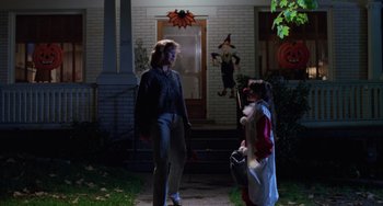 Movie still from “Halloween 4: The Return of Michael Myers” (1988), directed by Dwight H. Little – Two children dressed up in halloween costumes stand on the front porch of a house; Wide shot, Low angle