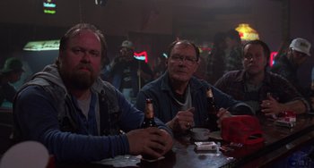 Movie still from “Halloween 4: The Return of Michael Myers” (1988), directed by Dwight H. Little – A group of men sitting at a table drinking beer; Medium shot, Low angle