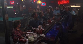 Movie still from “Halloween 4: The Return of Michael Myers” (1988), directed by Dwight H. Little – A group of people sitting at a bar with drinks; Wide shot, Over the shoulder angle