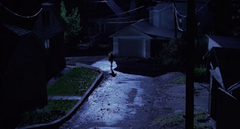 Movie still from “Halloween 4: The Return of Michael Myers” (1988), directed by Dwight H. Little – A person walking down a street at night; Extreme Wide shot, High angle