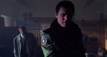 Movie still from “Halloween 4: The Return of Michael Myers” (1988), directed by Dwight H. Little – A man in a green jacket is standing in a room; Medium shot, Low angle