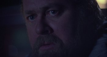 Movie still from “Halloween 4: The Return of Michael Myers” (1988), directed by Dwight H. Little – A person with a beard looking at the camera; Close Up shot, Over the shoulder angle