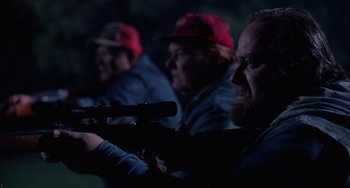 Movie still from “Halloween 4: The Return of Michael Myers” (1988), directed by Dwight H. Little – A group of people with guns in a dark room; Close Up shot, Over the shoulder angle