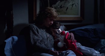Movie still from “Halloween 4: The Return of Michael Myers” (1988), directed by Dwight H. Little – A woman and a child sitting on a couch; Medium shot, Low angle