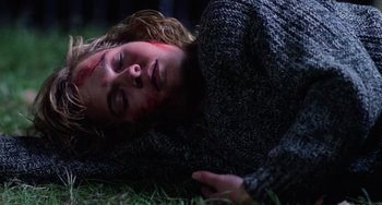 Movie still from “Halloween 4: The Return of Michael Myers” (1988), directed by Dwight H. Little – A woman laying in the grass with blood on her face; Close Up shot, High angle