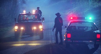 Movie still from “Halloween 4: The Return of Michael Myers” (1988), directed by Dwight H. Little – Two police cars and a tow truck on a foggy night; Wide shot, Low angle