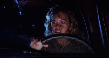 Movie still from “Halloween 4: The Return of Michael Myers” (1988), directed by Dwight H. Little – A young woman driving a car in the dark at night; Close Up shot, Low angle